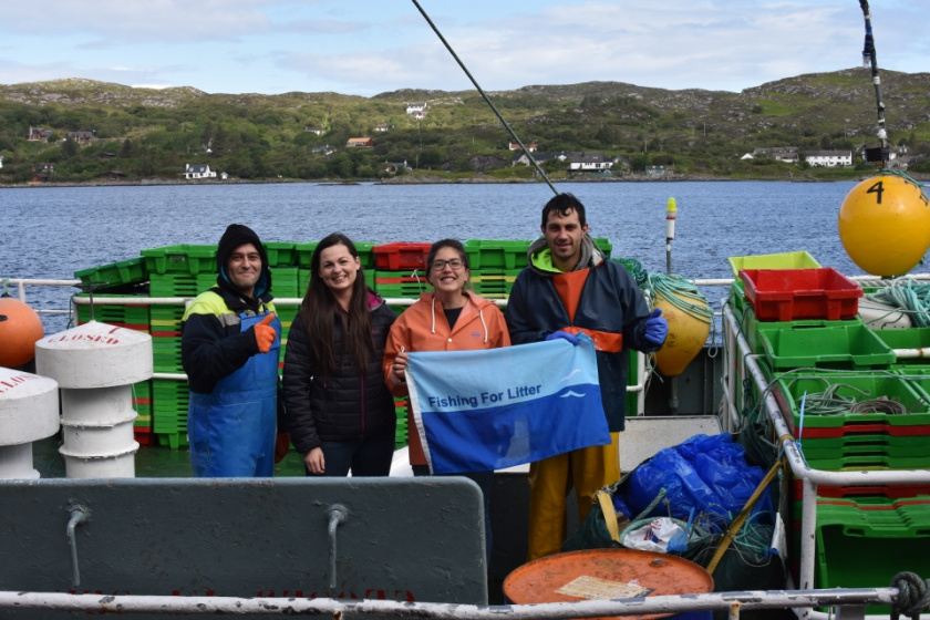 Fishermen and KIMO representatives hold the KIMO flag on board one of the 320 Fishing for Litter vessels around the UK.