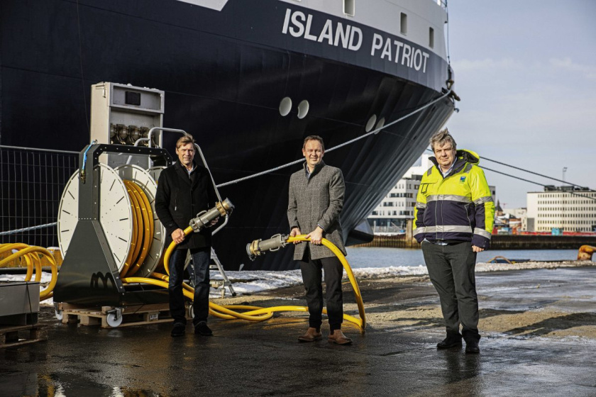 Three men holding the shore side power connection next to the Island Patriot ship at the harbour in Esbjerg, Denmark